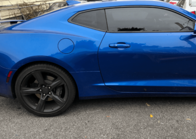 Blue sports car parked on asphalt, black wheels, tinted windows.