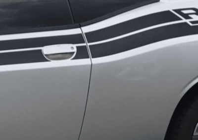 Silver Dodge Challenger car door with black racing stripe and door handle.