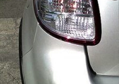 Silver car's rear quarter panel and tail light.