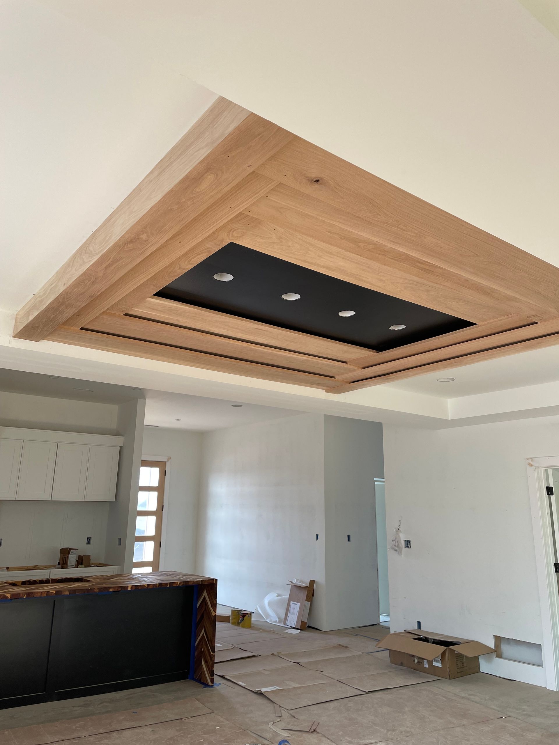 Wood and black ceiling design with recessed lighting in a room under construction.