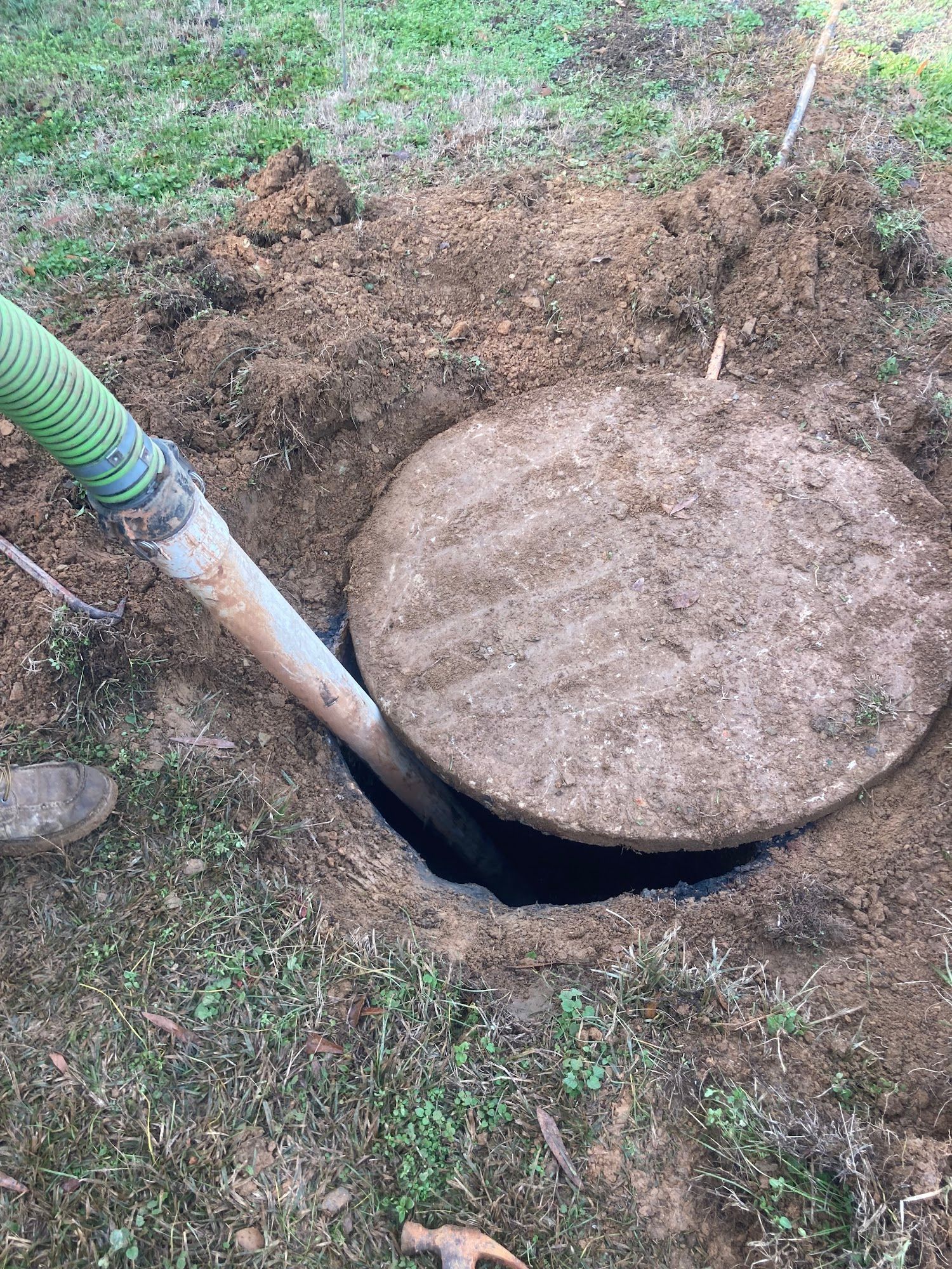 A manhole cover is being pumped into a hole in the ground.