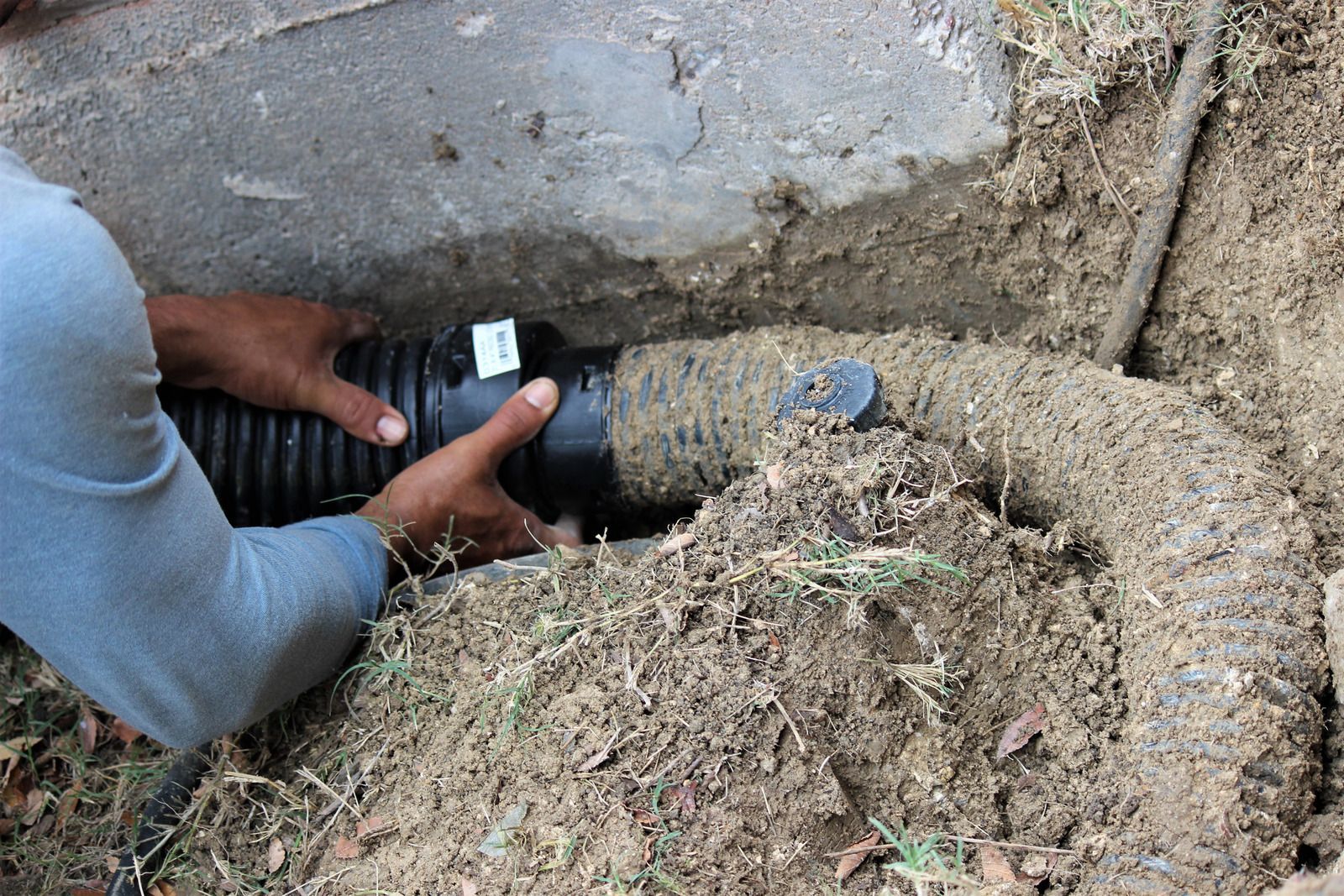 A man is fixing a pipe in the dirt.