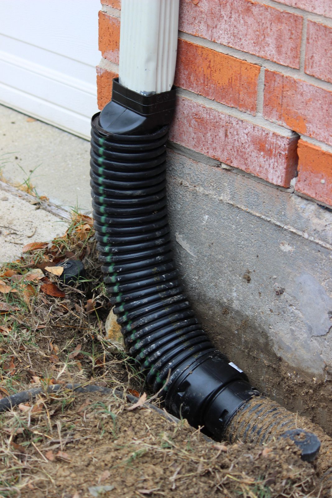 A black rain gutter is attached to the side of a brick building.