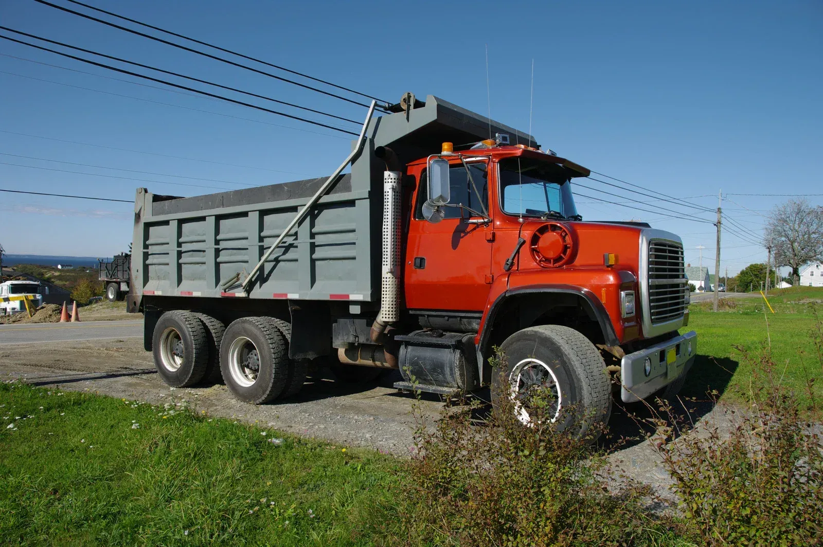 Blue dumpster on a truck, tilted up, filled with debris, parked on a residential street.
