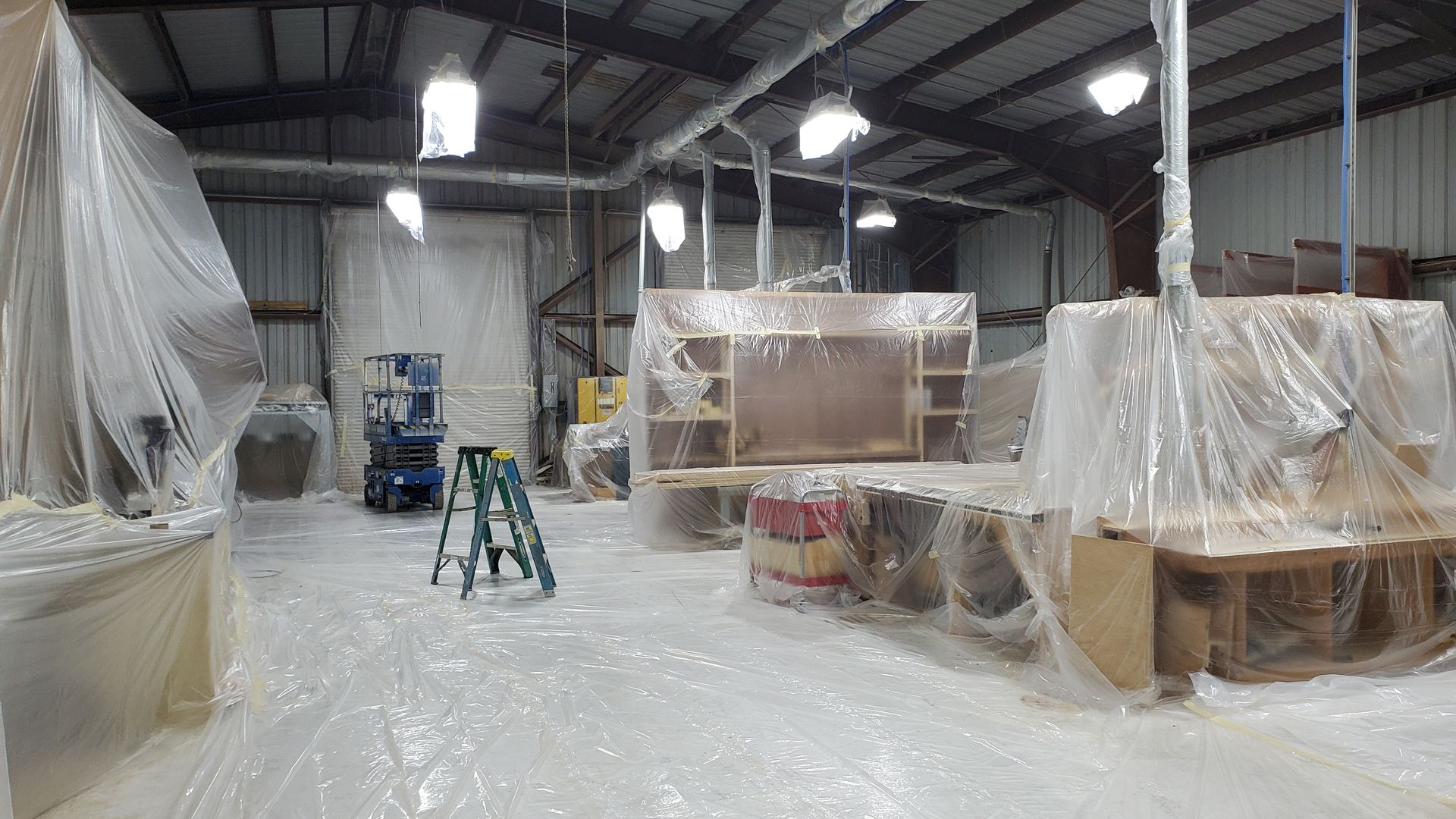 A warehouse filled with lots of plastic wrap and a ladder.