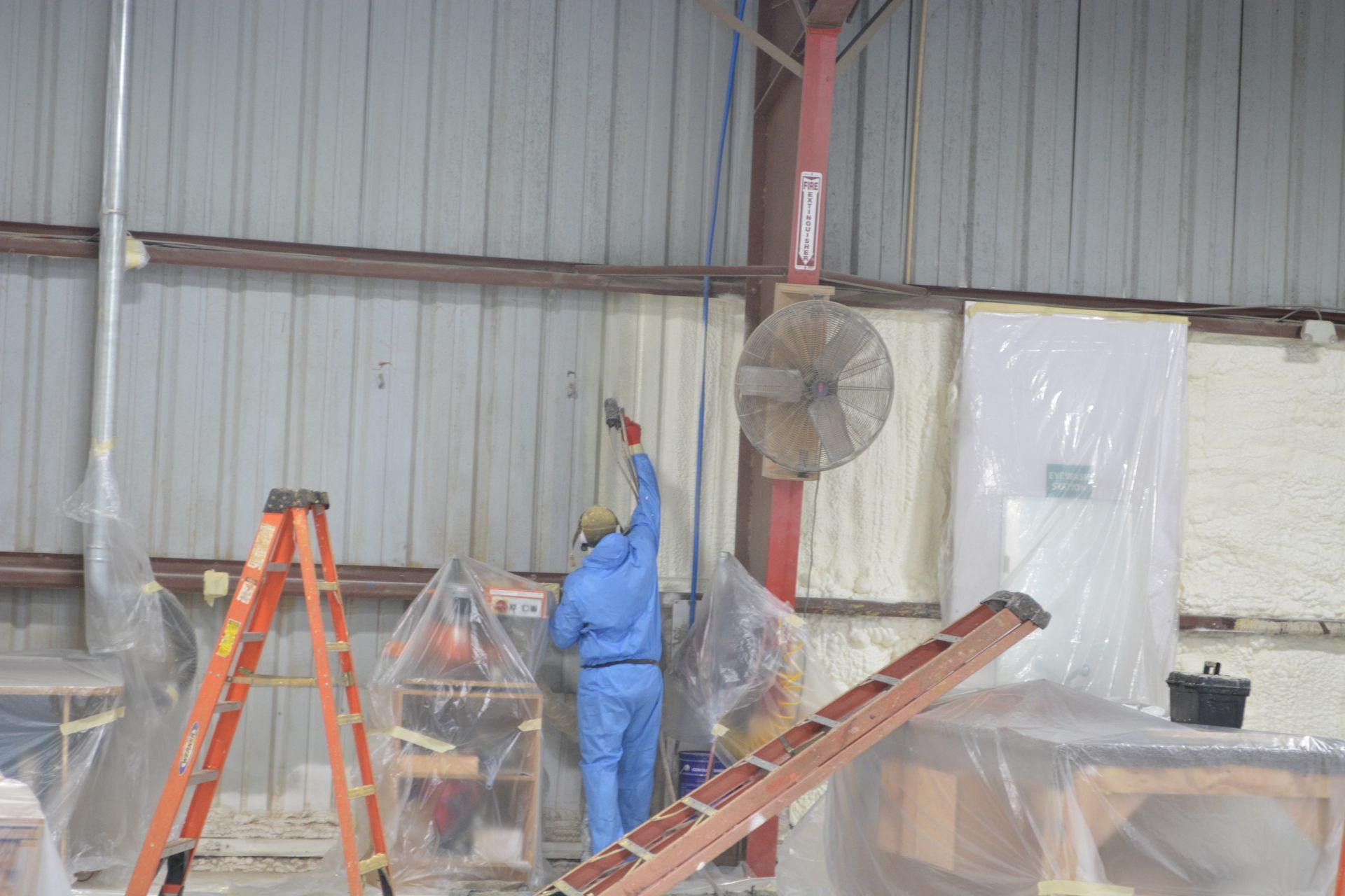 A man is painting a wall in a warehouse.