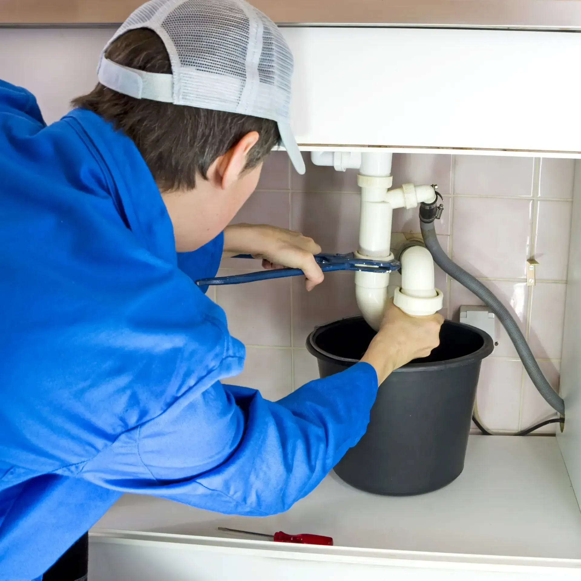 ReplacementZone Plumbing  - A man is fixing a sink with a pair of pliers