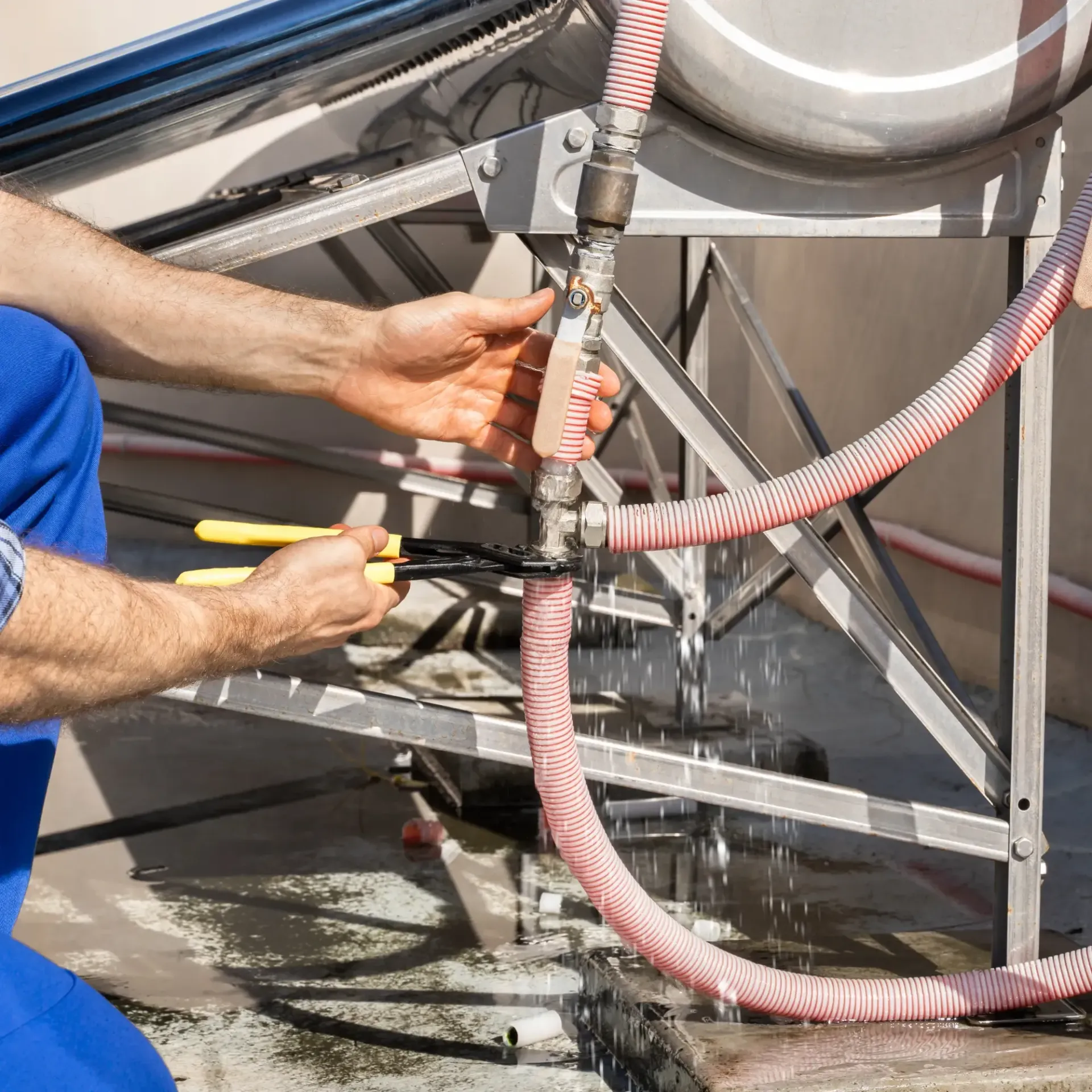 ReplacementZone Plumbing  - A man is working on a water heater with a pair of pliers.