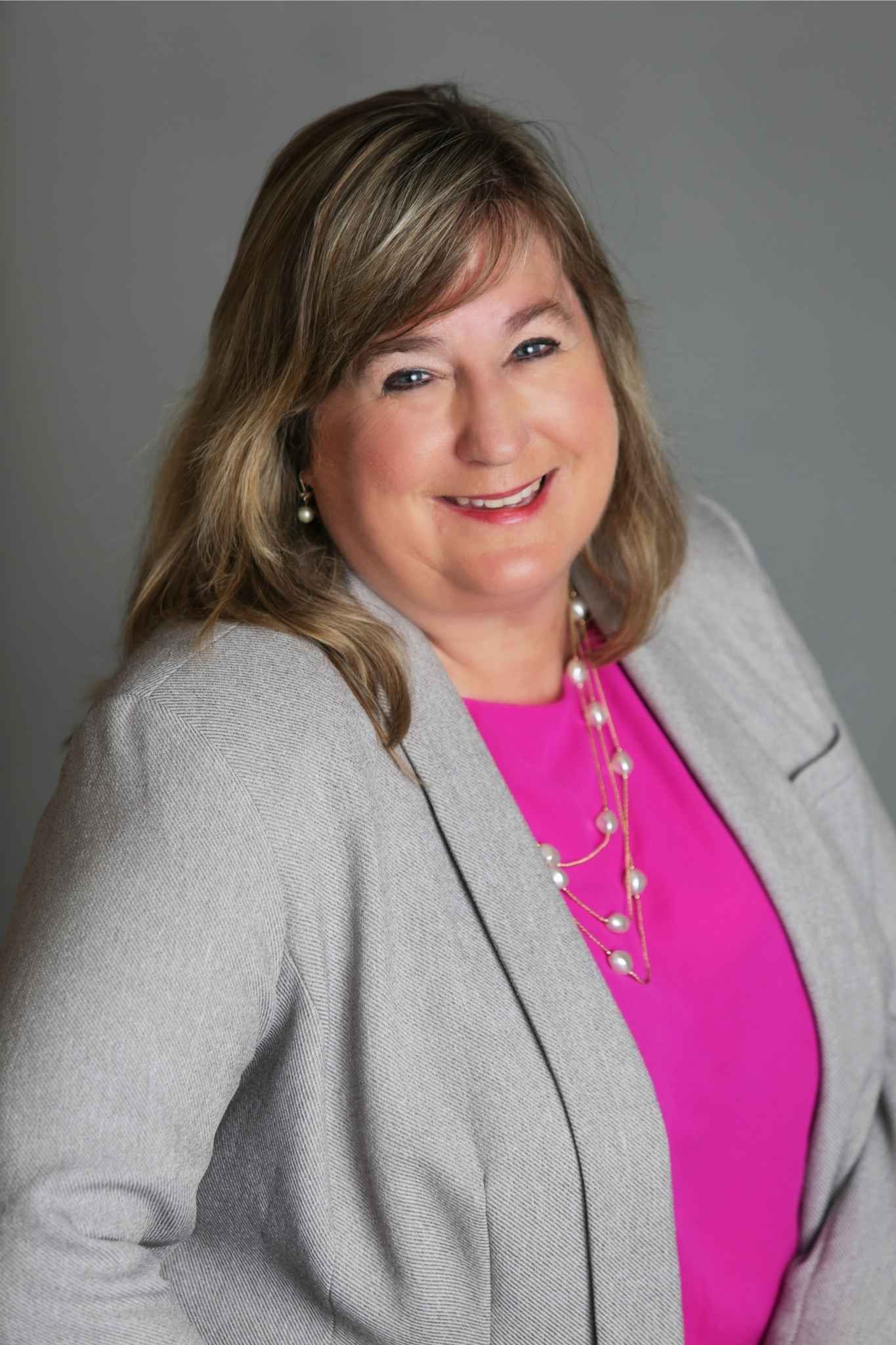 A woman in a black jacket and purple shirt is smiling for the camera.