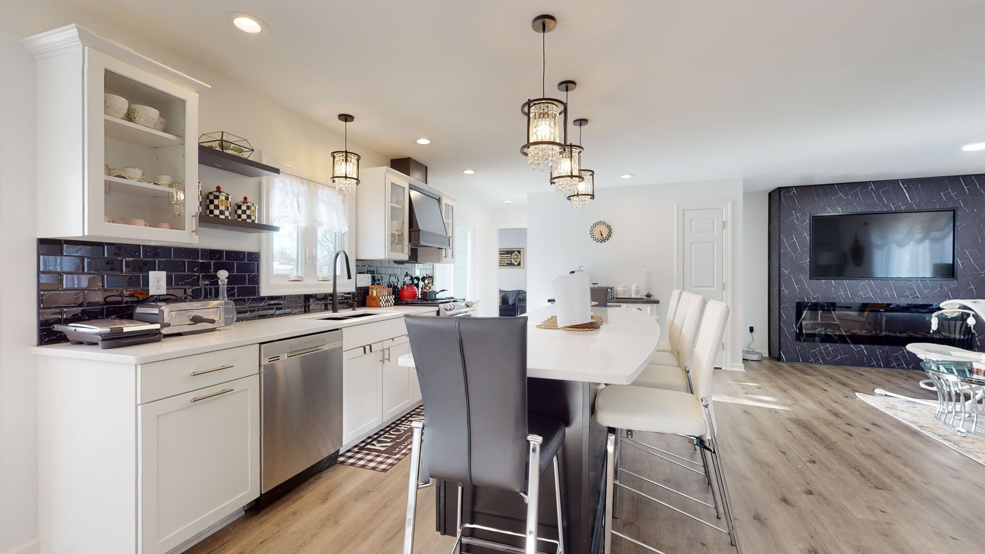 A bright kitchen featuring white cabinets, stainless steel appliances, a center island with stools, and a black accent wall.