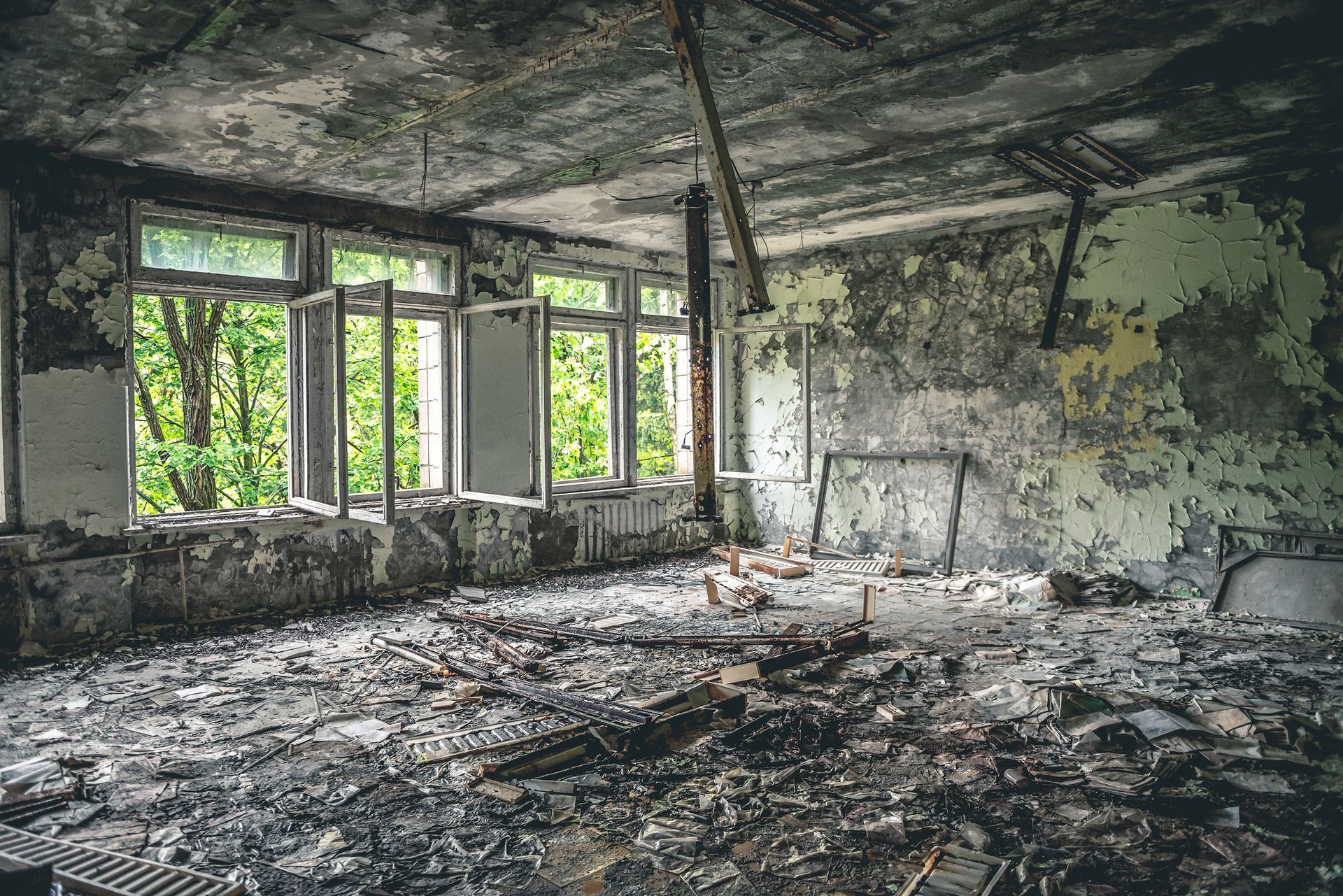 Abandoned room with smoke-stained walls, peeling paint, and debris after severe fire damage.