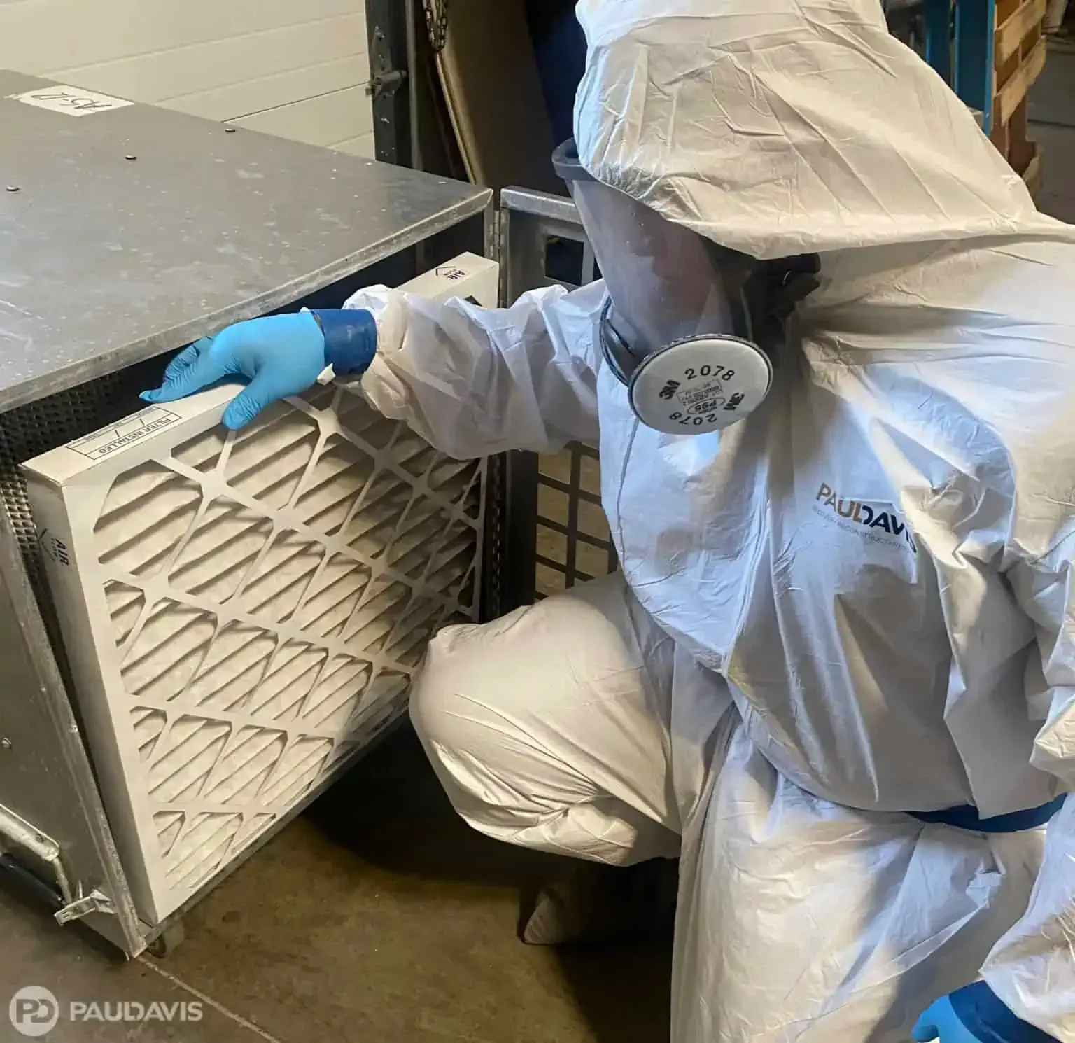 Technician in PPE inspecting HVAC filter during professional mould remediation