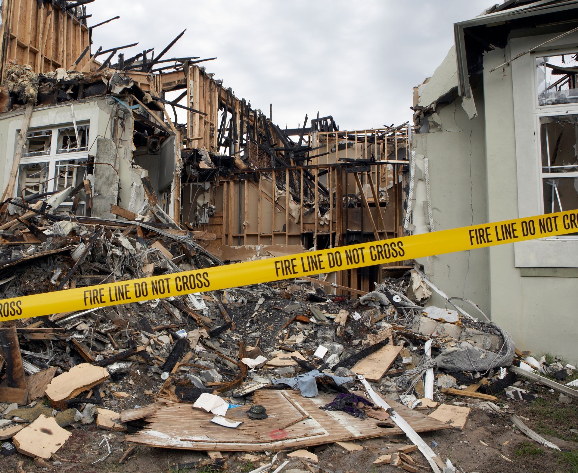A building reduced to charred ruins and debris, cordoned off by yellow 
