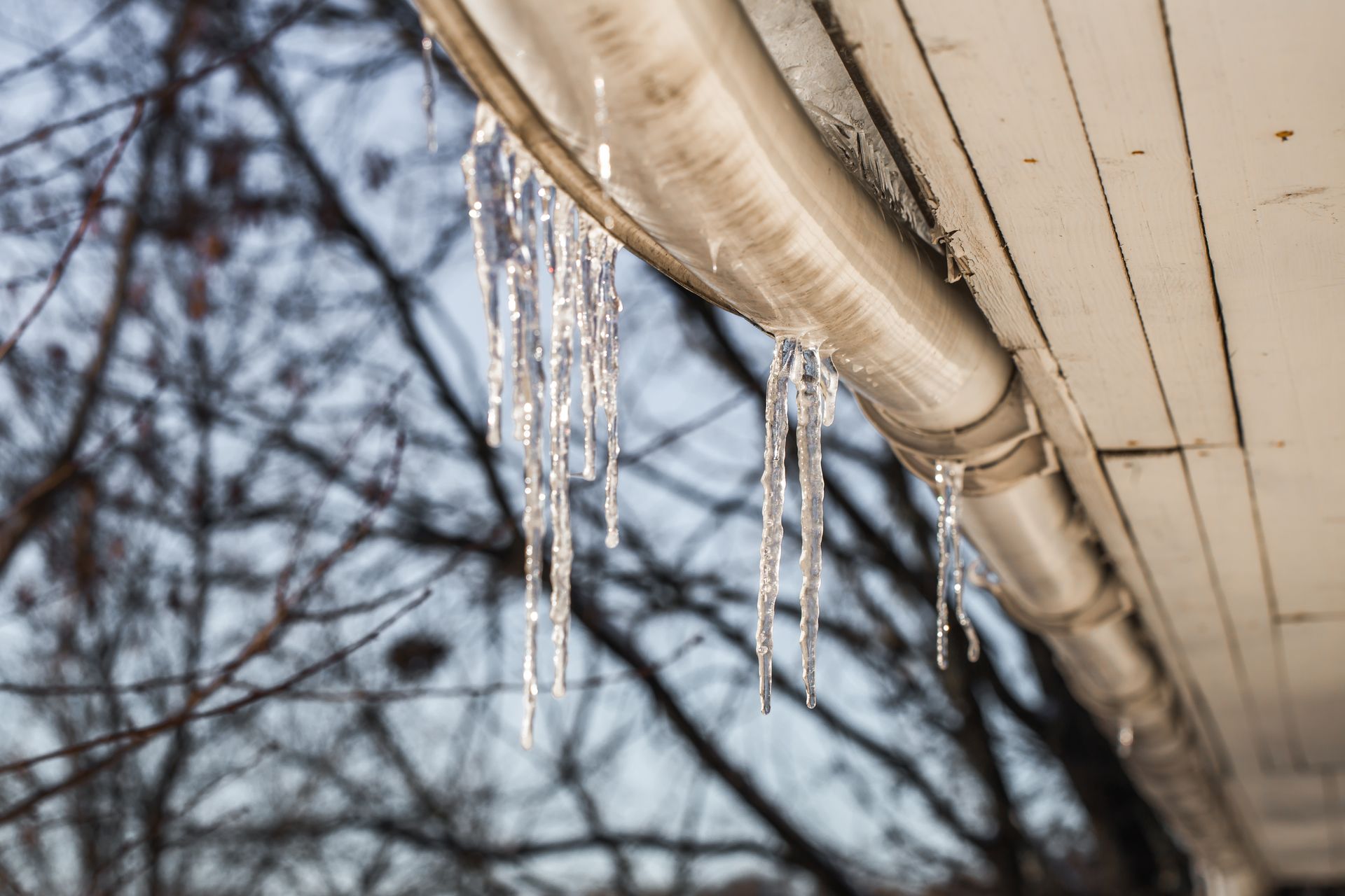 Glaçons sur le rebord d’un toit, illustrant le risque de dique de glace en hiver.