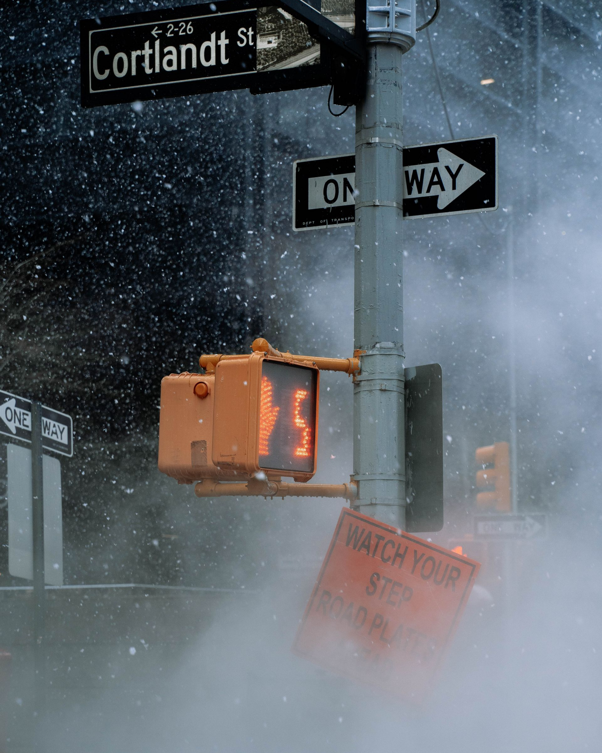 Tempête de neige à un carrefour urbain avec signal d’arrêt et faible visibilité due à la vapeur.