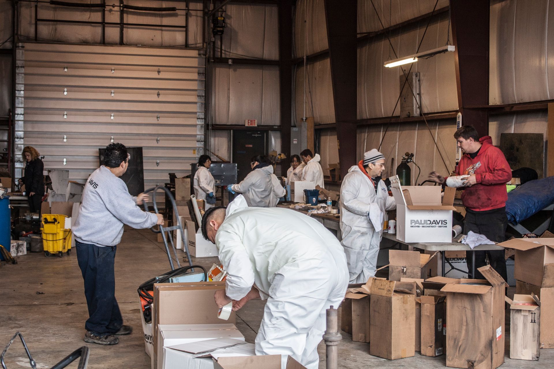 Volunteers in a warehouse package boxes of supplies for distribution.