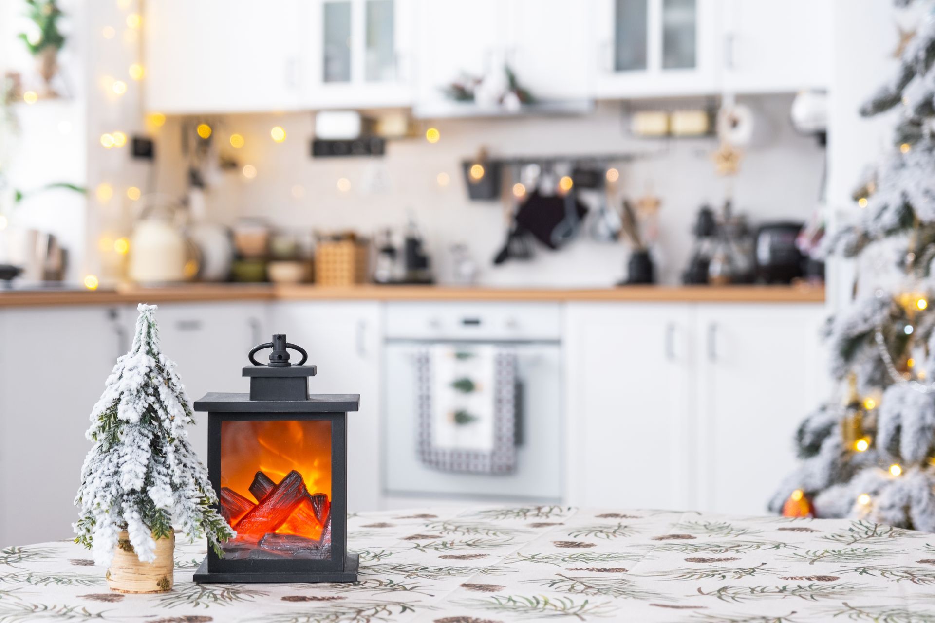 Cuisine festive avec guirlandes, lanterne chauffante et sapin — rappel des risques d’incendie.