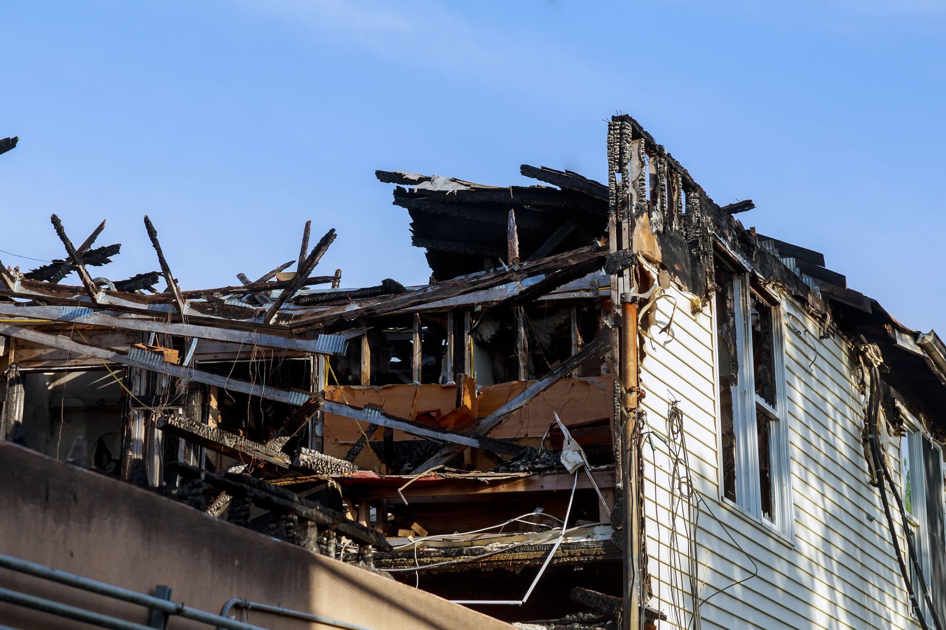 Fire-damaged house with collapsed roof and charred siding after a major residential blaze.
