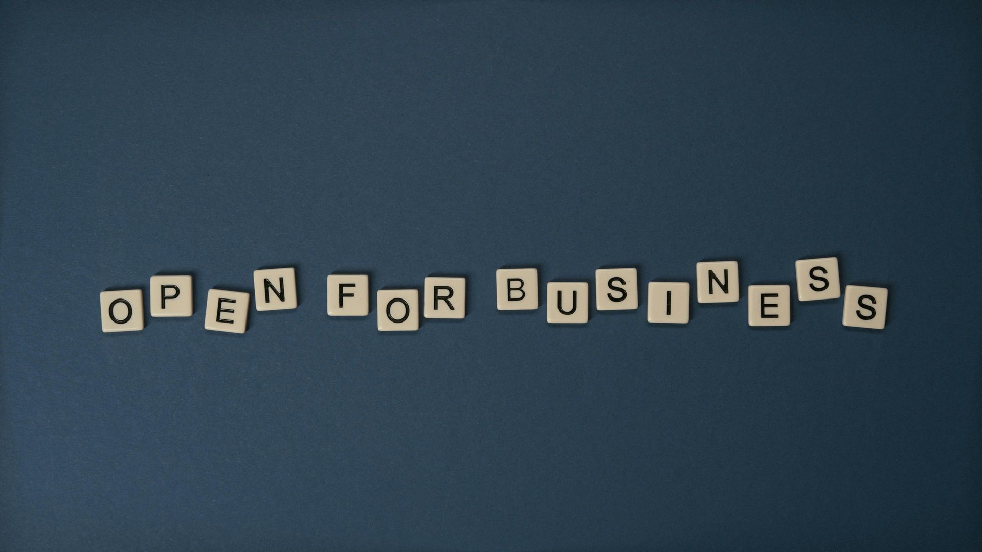 Scrabble-type wooden letters on a dark grey background, spelling out the phrase, 