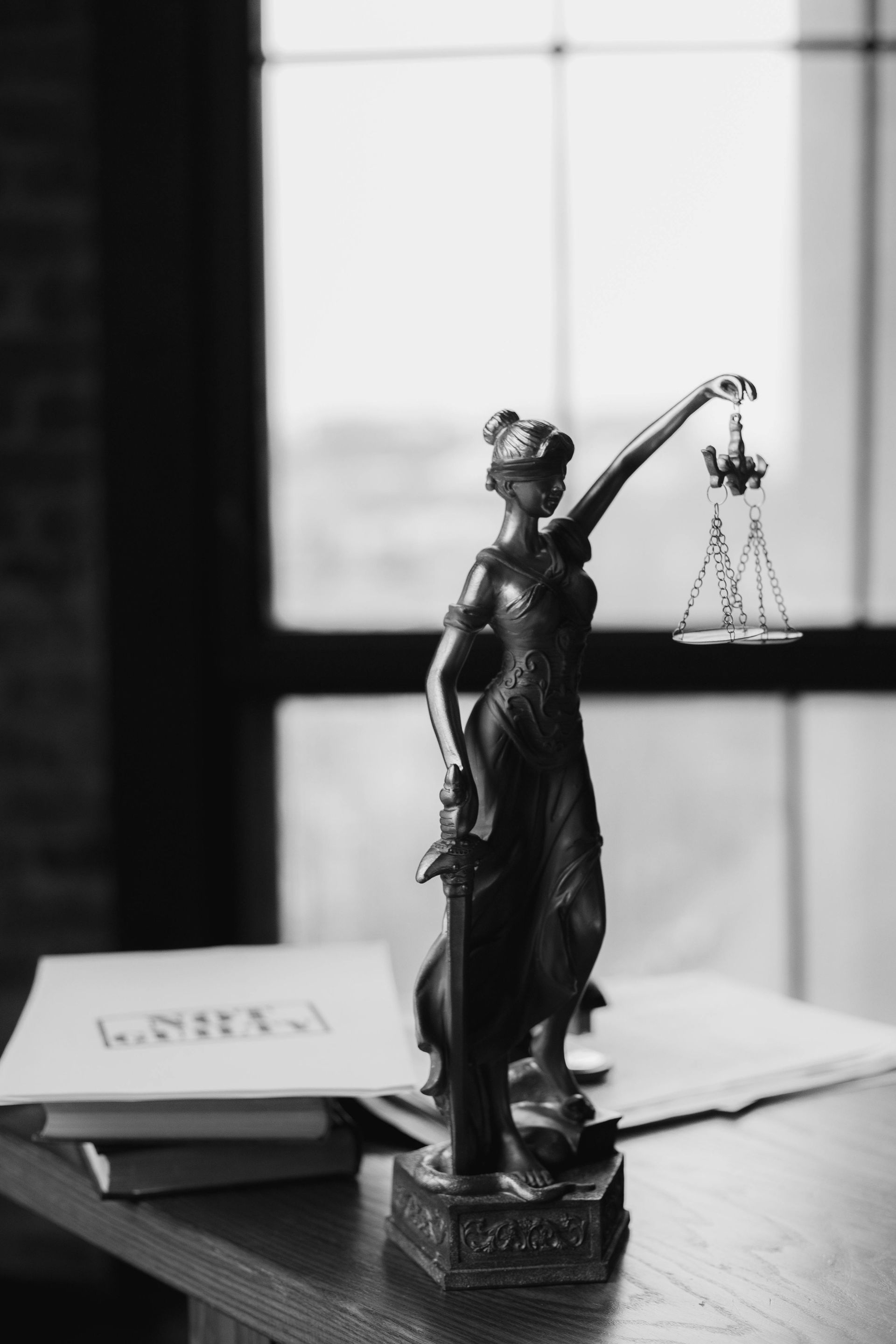 Lady Justice statue on a polished wood desk in a law firm.