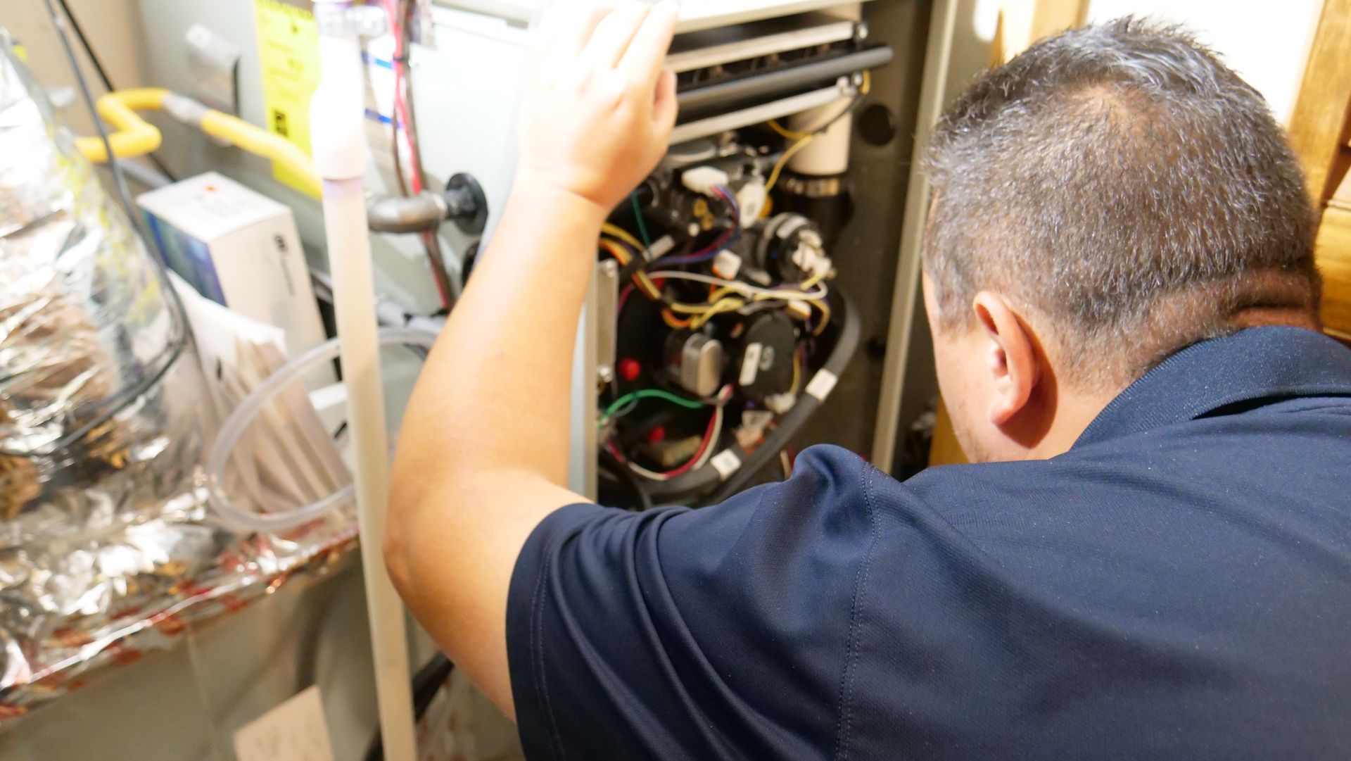 A man is working on an air conditioner in a room.