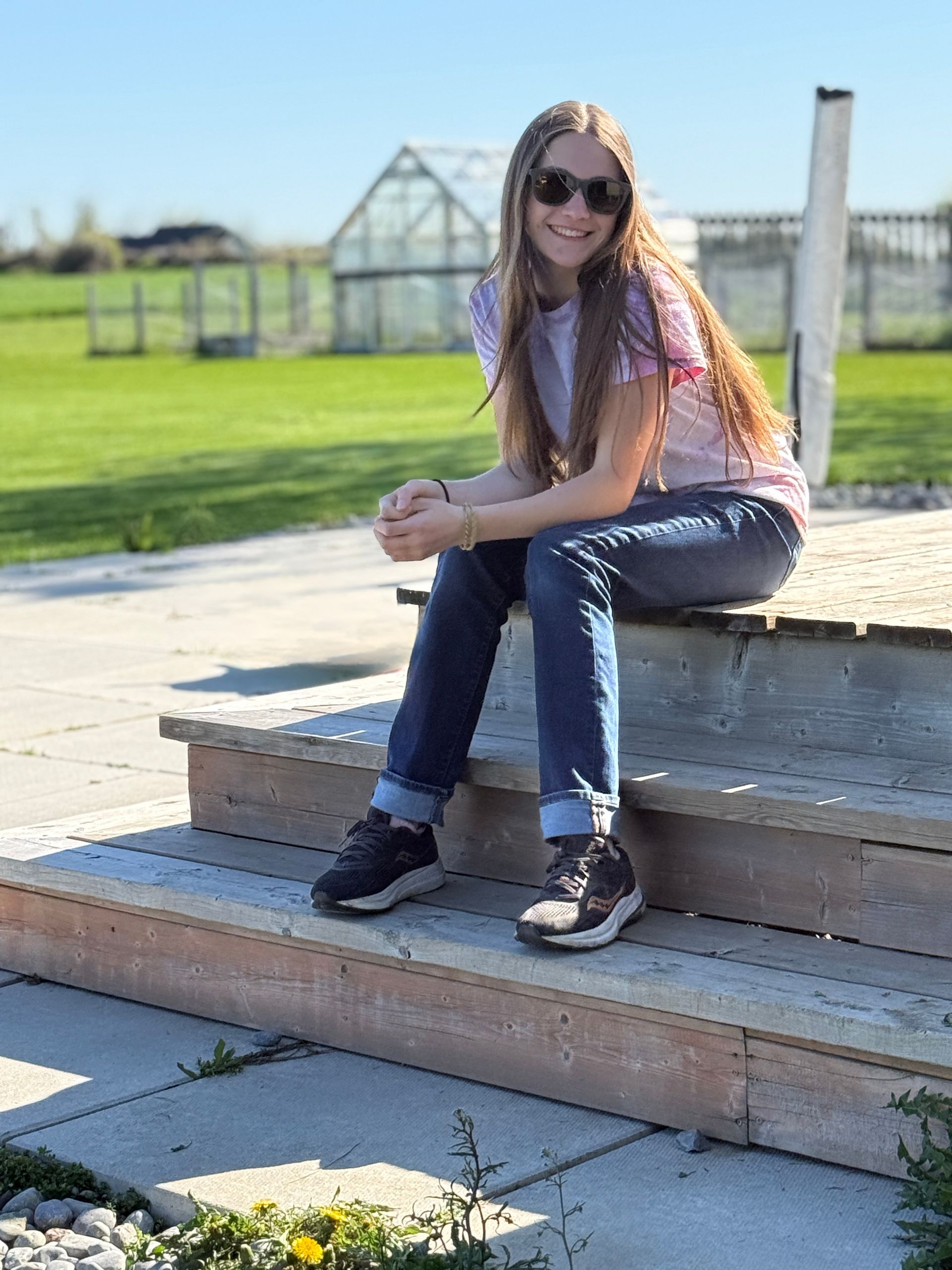 Woman sitting, looking at mountain range, glacier, and lake.
