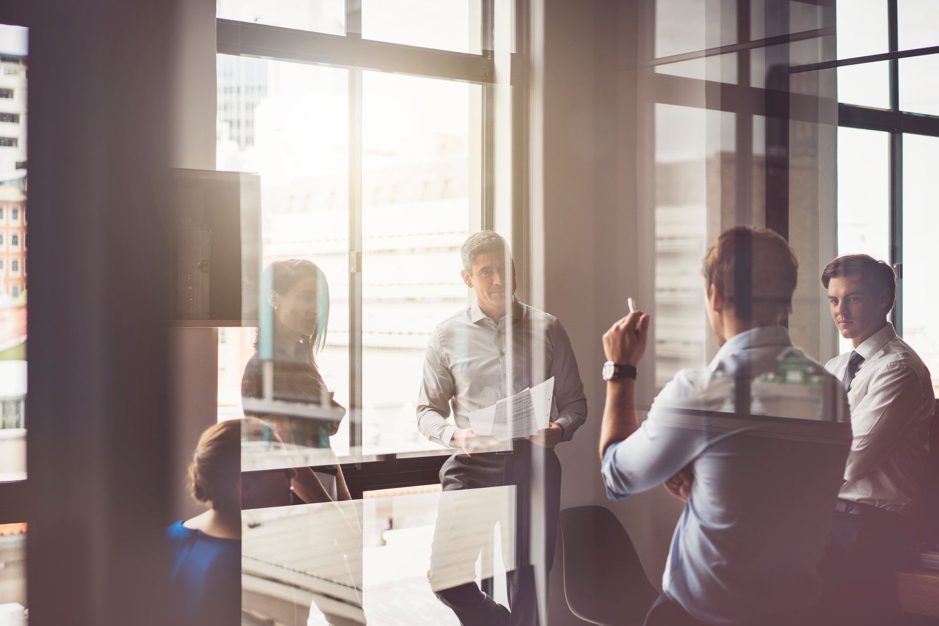 Business team in a modern office meeting, discussing paperwork, natural light.