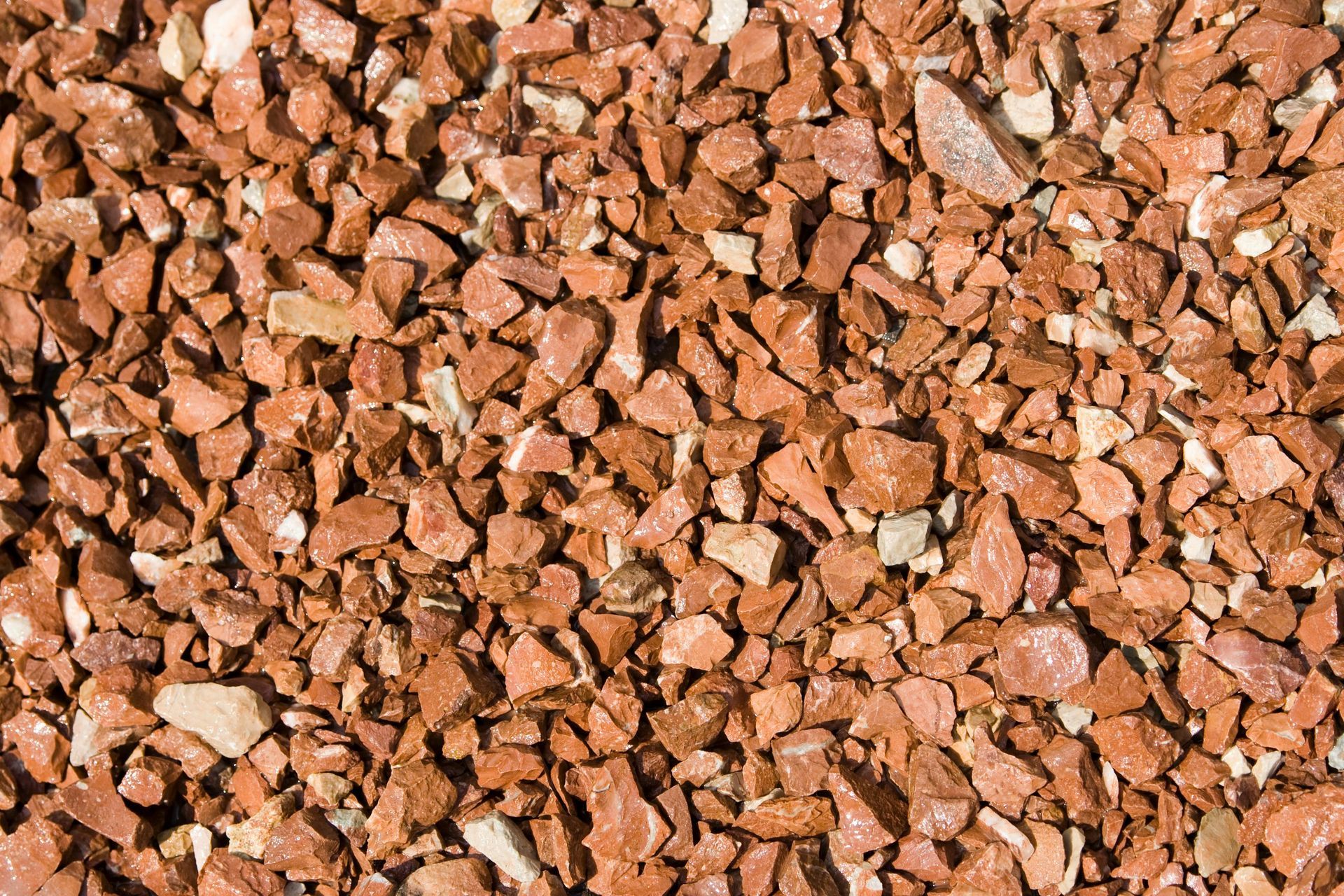 Woman in straw hat smiles, holding wine glass near a lake.