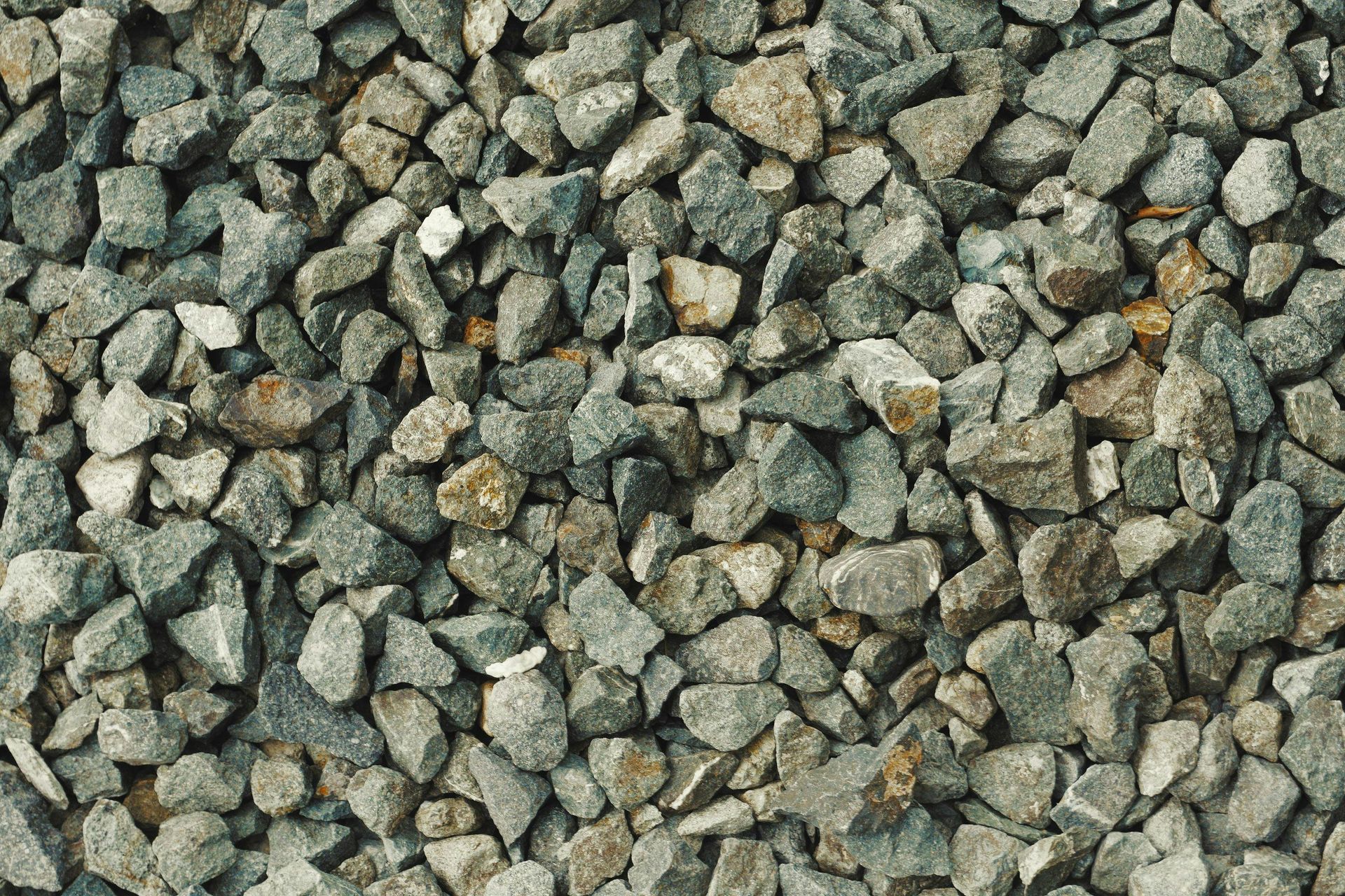 Woman in straw hat smiles, holding wine glass near a lake.