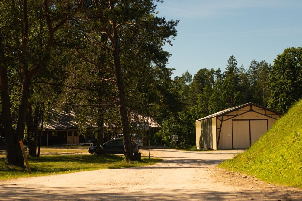 Woman in straw hat smiles, holding wine glass near a lake.
