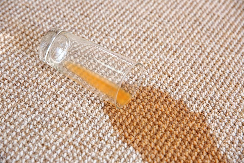 A Glass Of Orange Juice Has Spilled On A Carpet — Lindfield’s Big Red Carpet Cleaning & Pest Control in Harrington, NSW