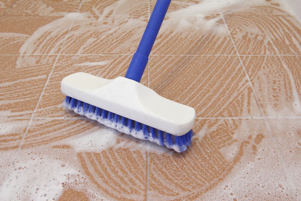 A Blue And White Brush Is Cleaning A Tiled Floor — Lindfield’s Big Red Carpet Cleaning & Pest Control in Tuncurry, NSW