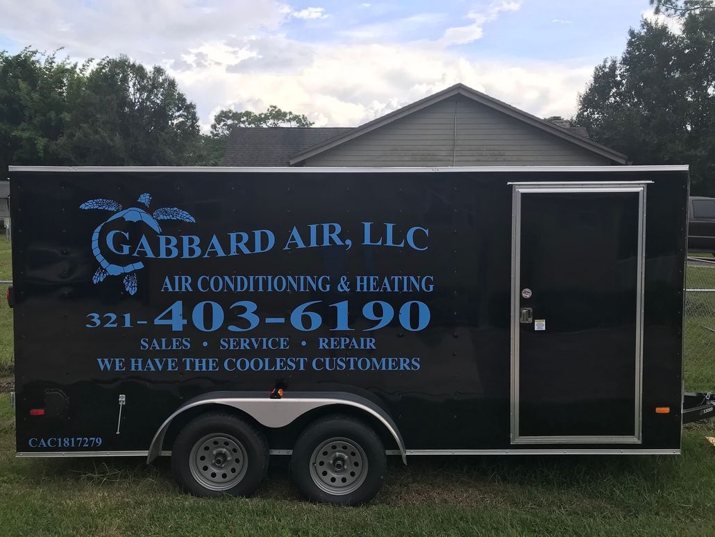 A black trailer for garbard air llc air conditioning and heating is parked in front of a house.