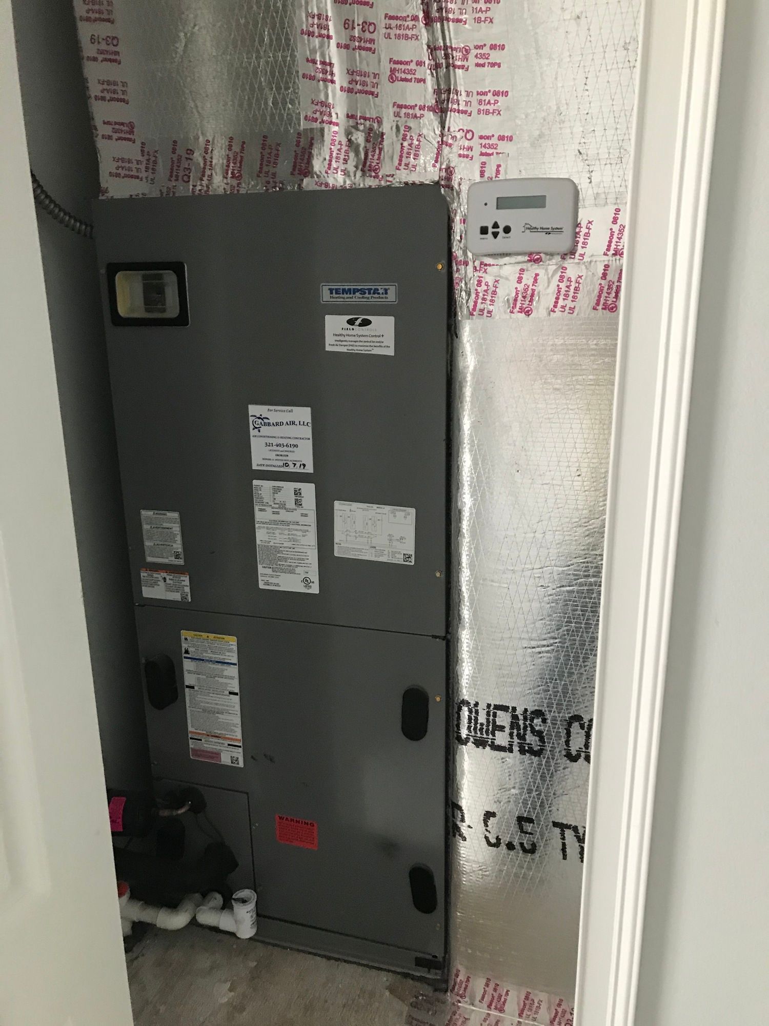 A room with a heater and a thermostat on the wall.