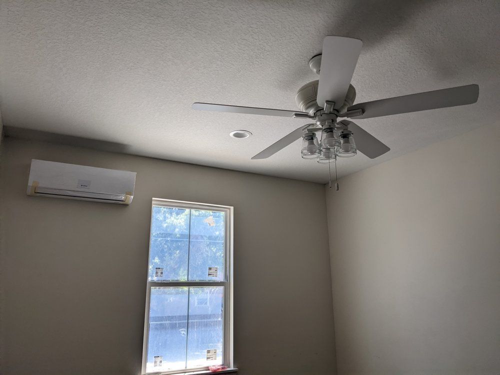 A bedroom with a ceiling fan and a window.