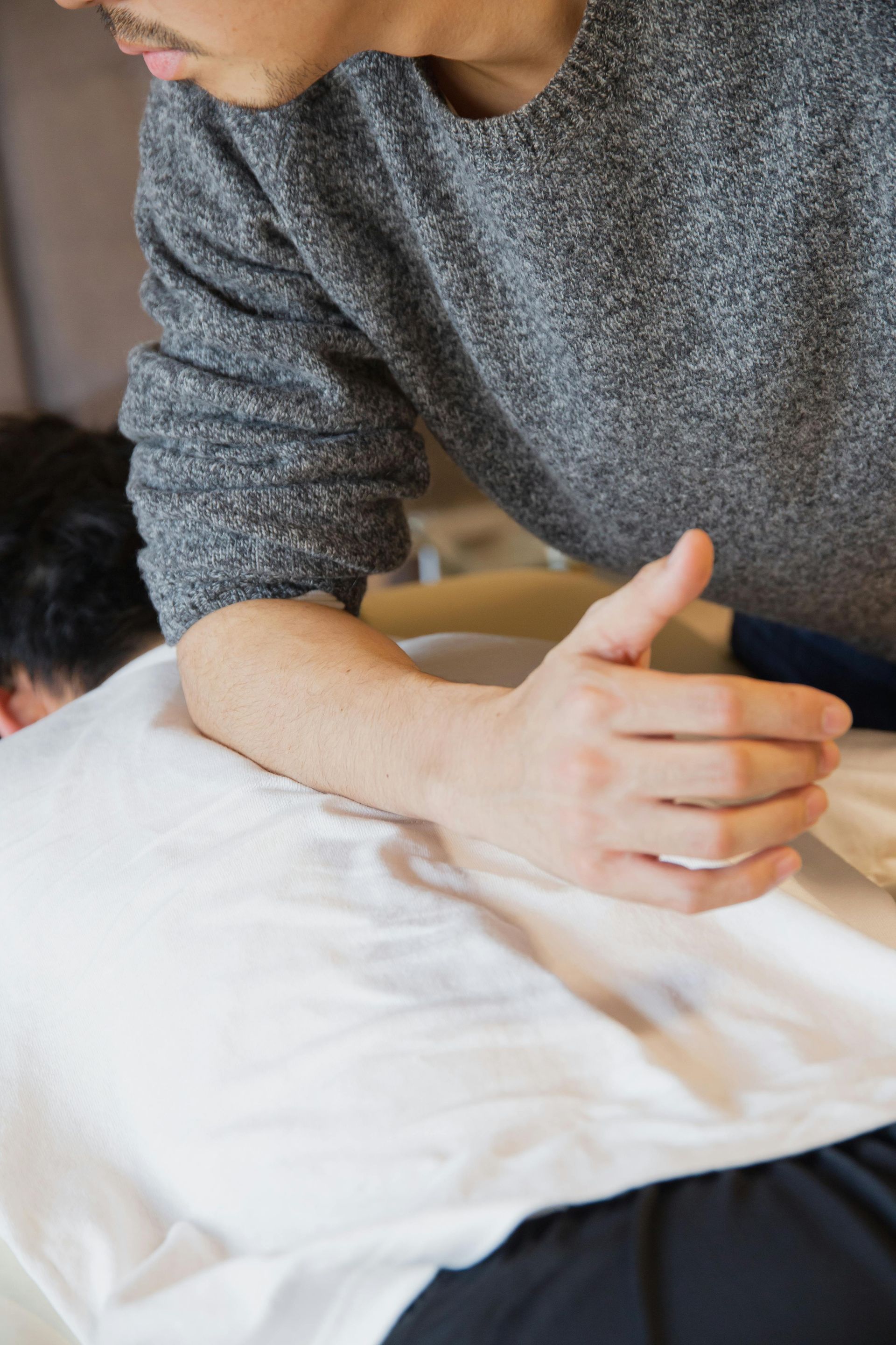 Person giving a back massage to someone lying on a white towel