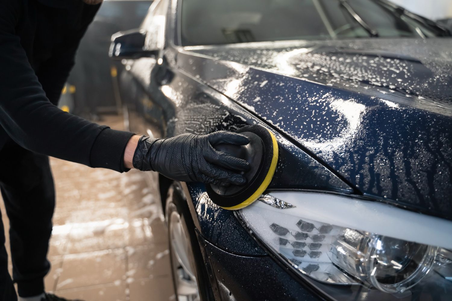 A person is polishing a car with a sponge.