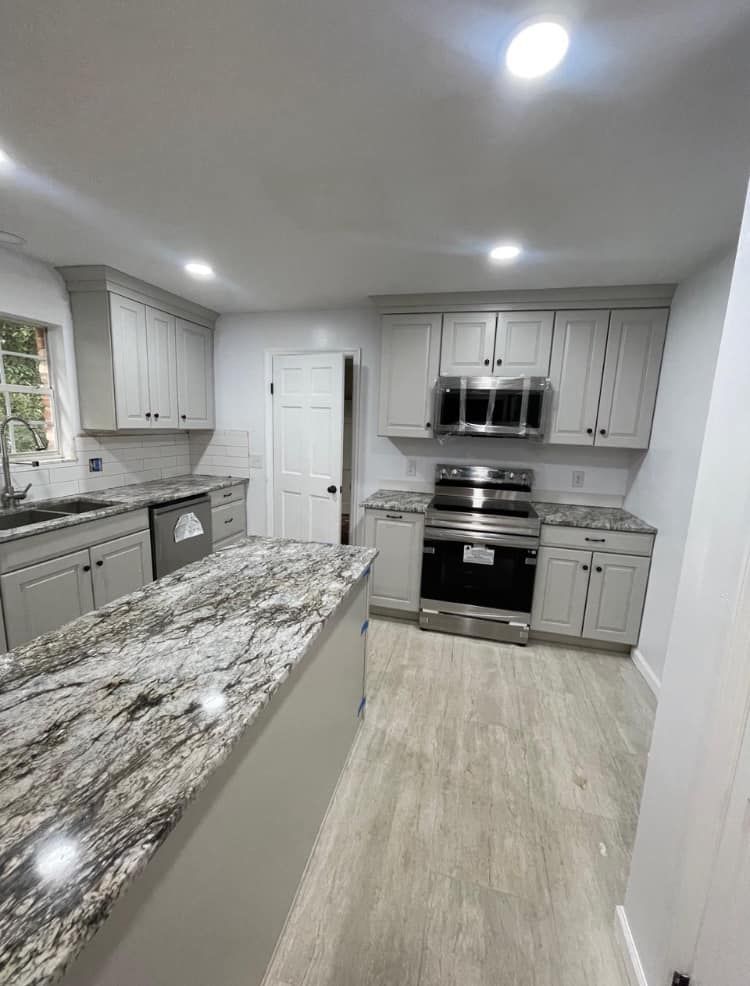 Modern kitchen with gray cabinets, stainless steel appliances, and a large island with a granite countertop.