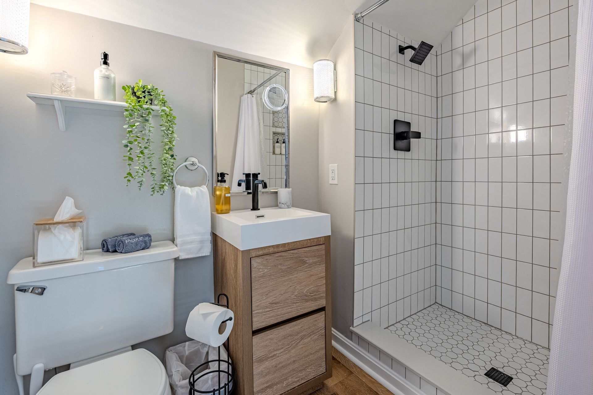 A bathroom with a toilet , sink , shower and mirror.