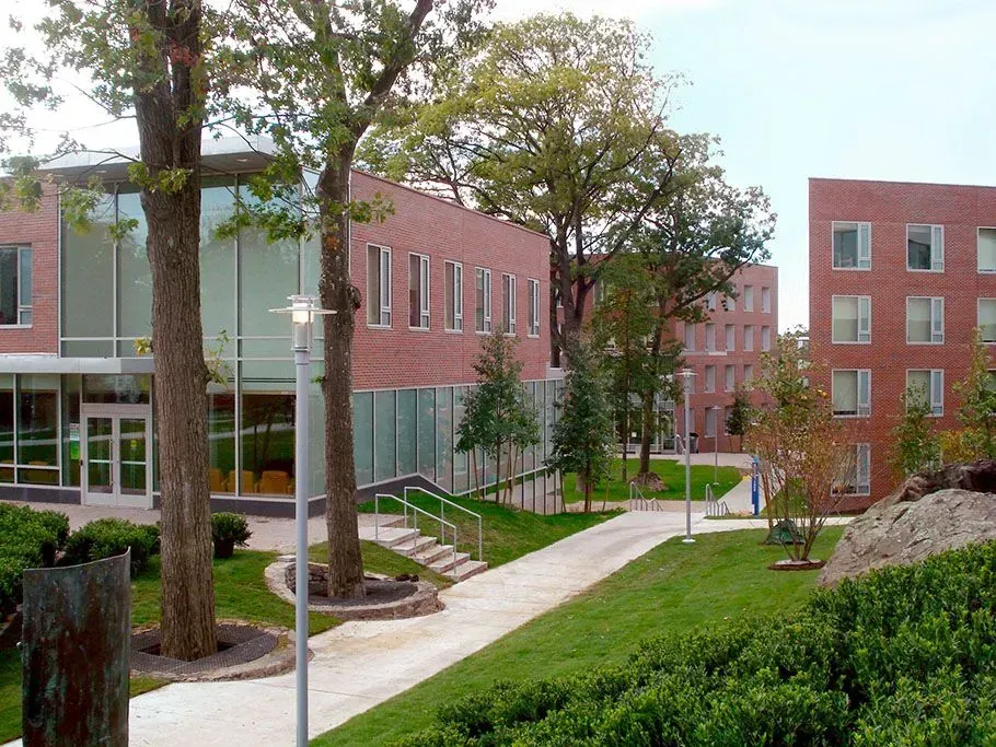 Modern brick campus buildings with trees, walkways, and a landscaped courtyard