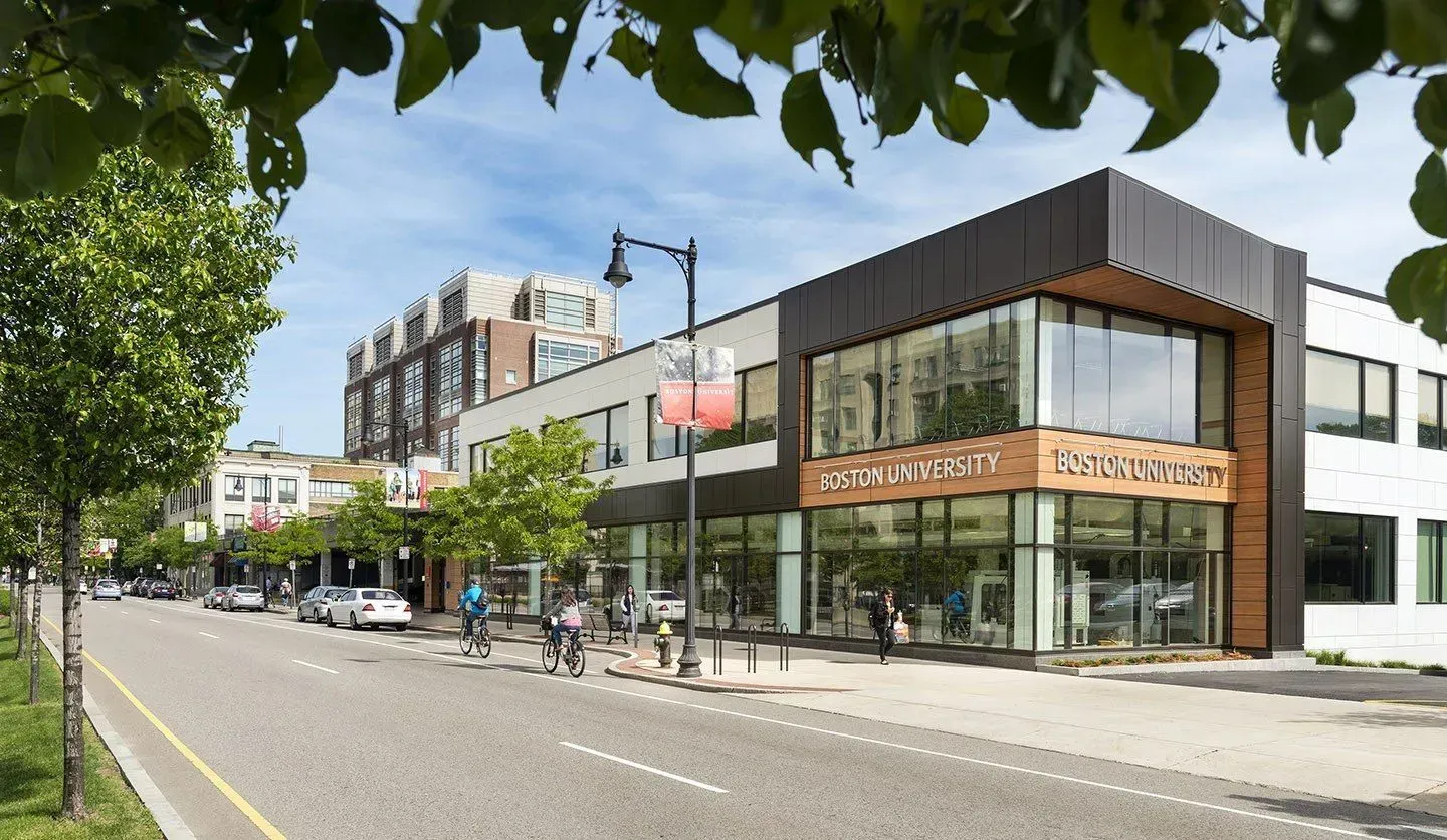 Modern corner storefront on a tree-lined city street with large windows and pedestrians nearby