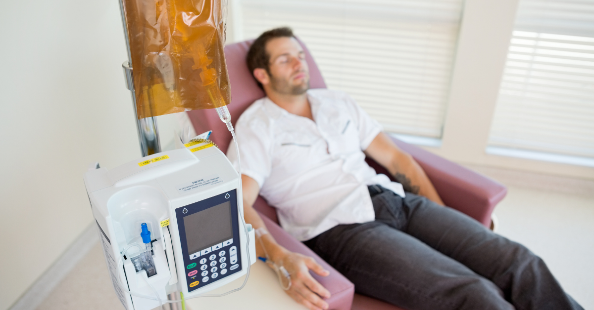A man is laying in a hospital chair with an iv in his arm.