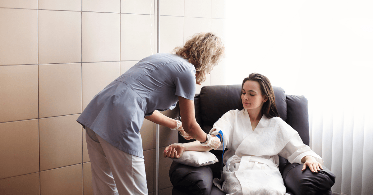 A woman is sitting in a chair with a nurse standing next to her.