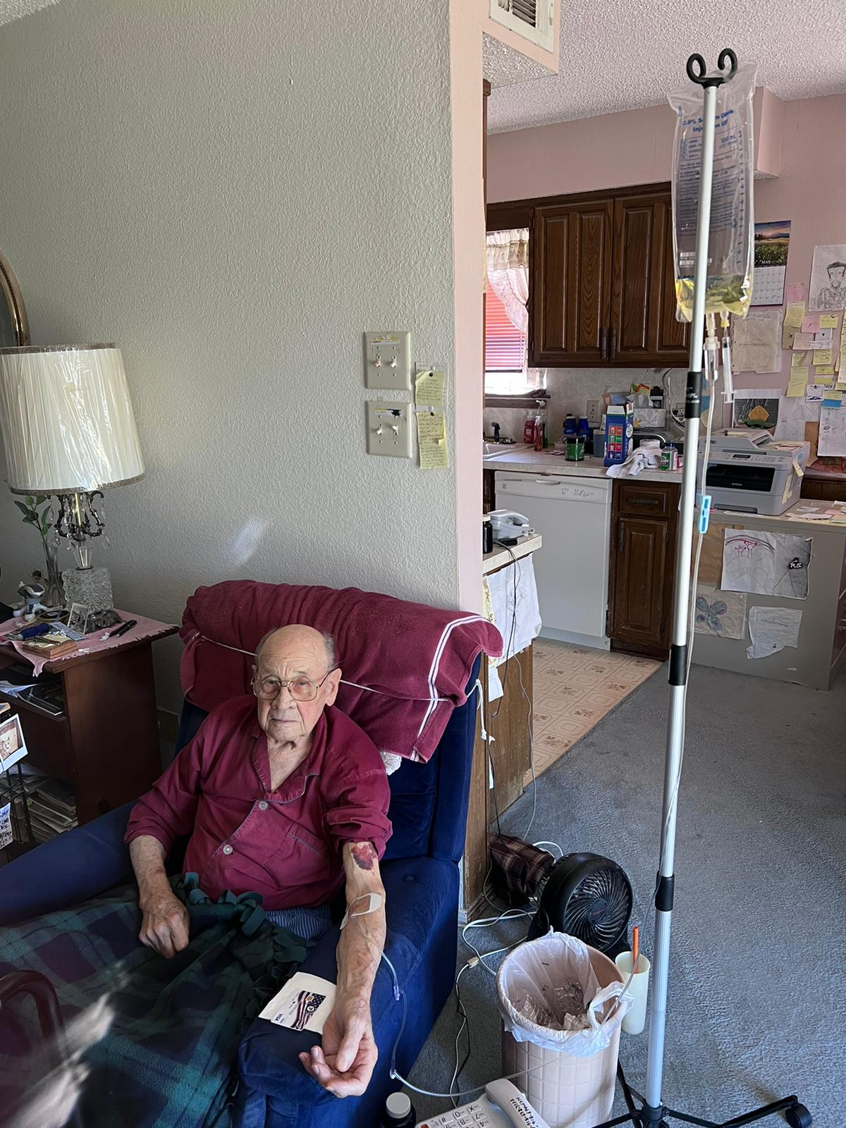 An elderly man is sitting in a chair with an iv in his arm.