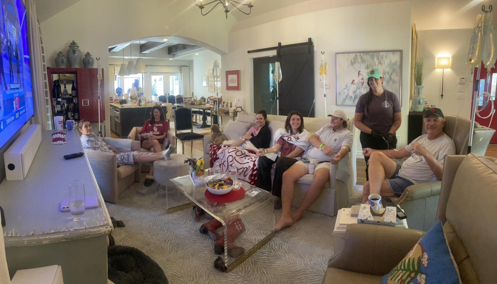 A group of people are sitting in a living room watching a game on a television.