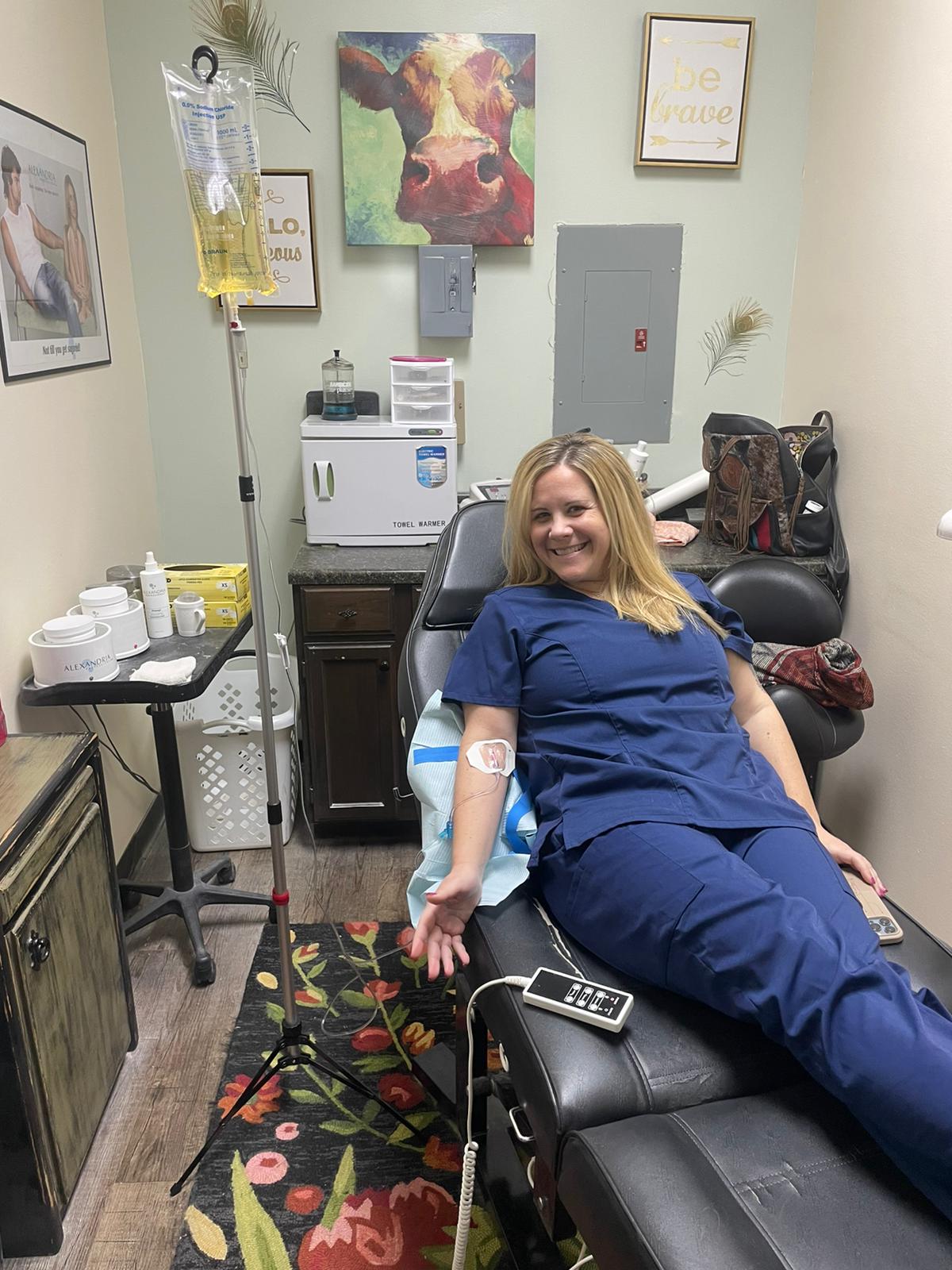 A woman is sitting in a chair with an iv in her arm.