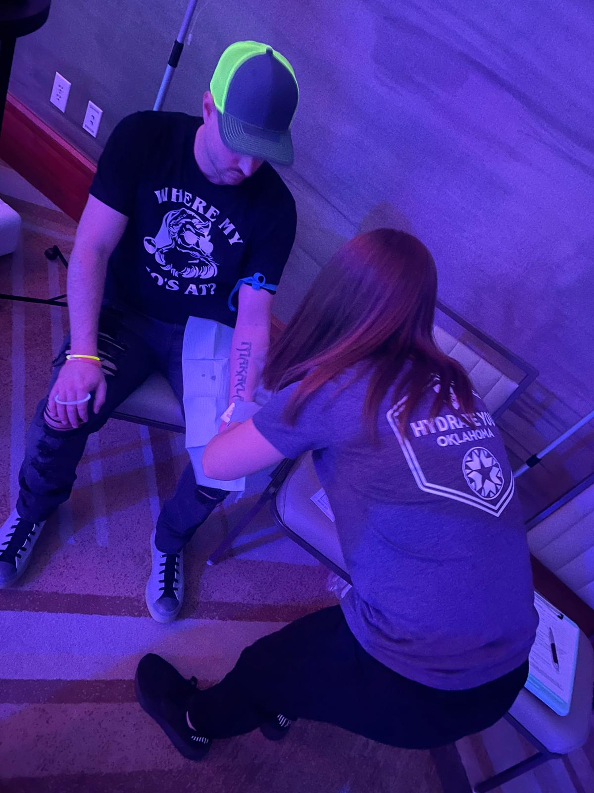 A woman in a purple shirt has a tattoo on a man 's arm
