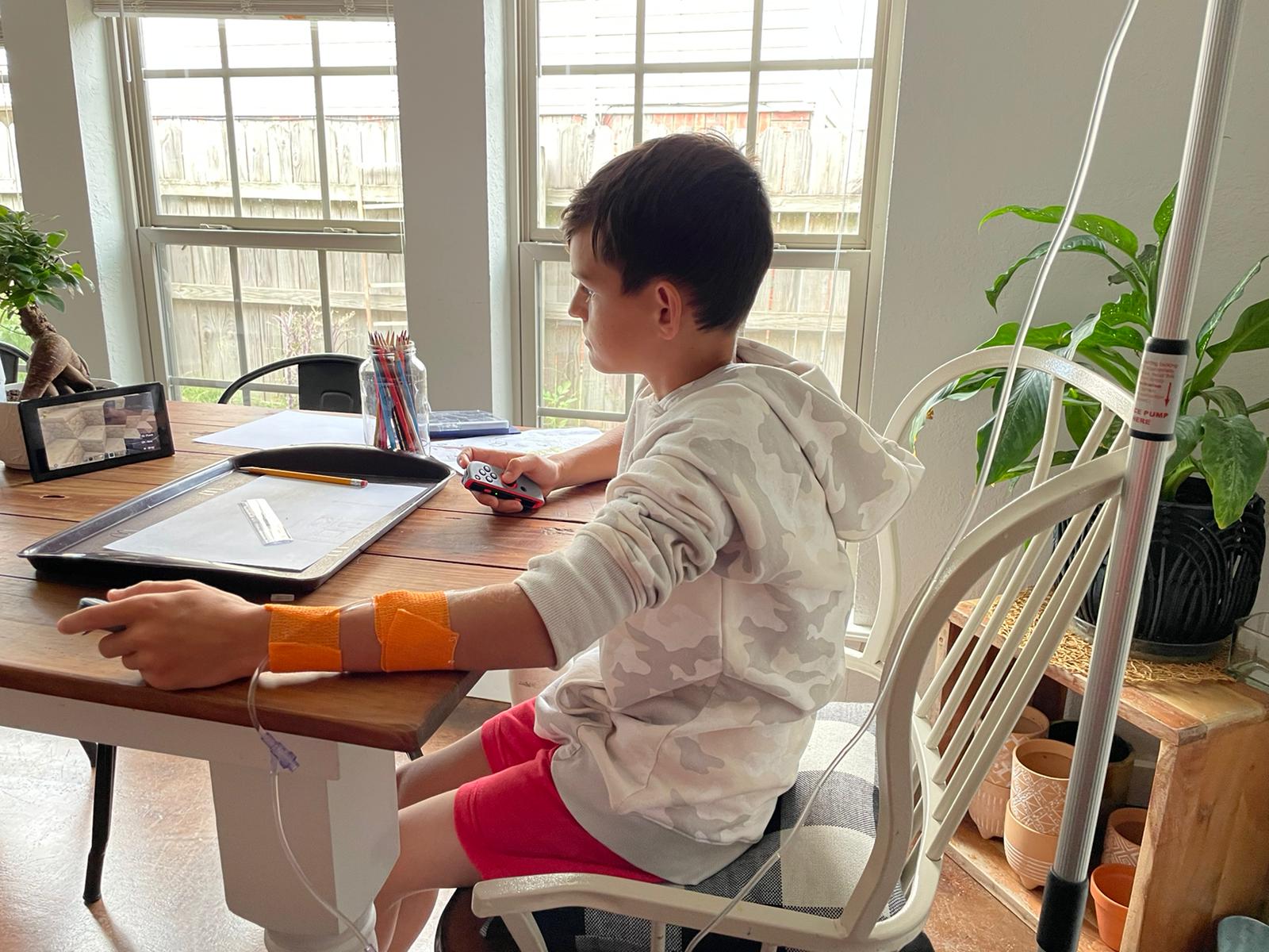 A young boy is sitting at a table playing a video game.