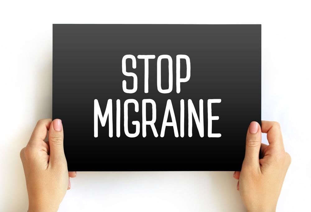 A person is holding a sign that says `` stop migraine ''.