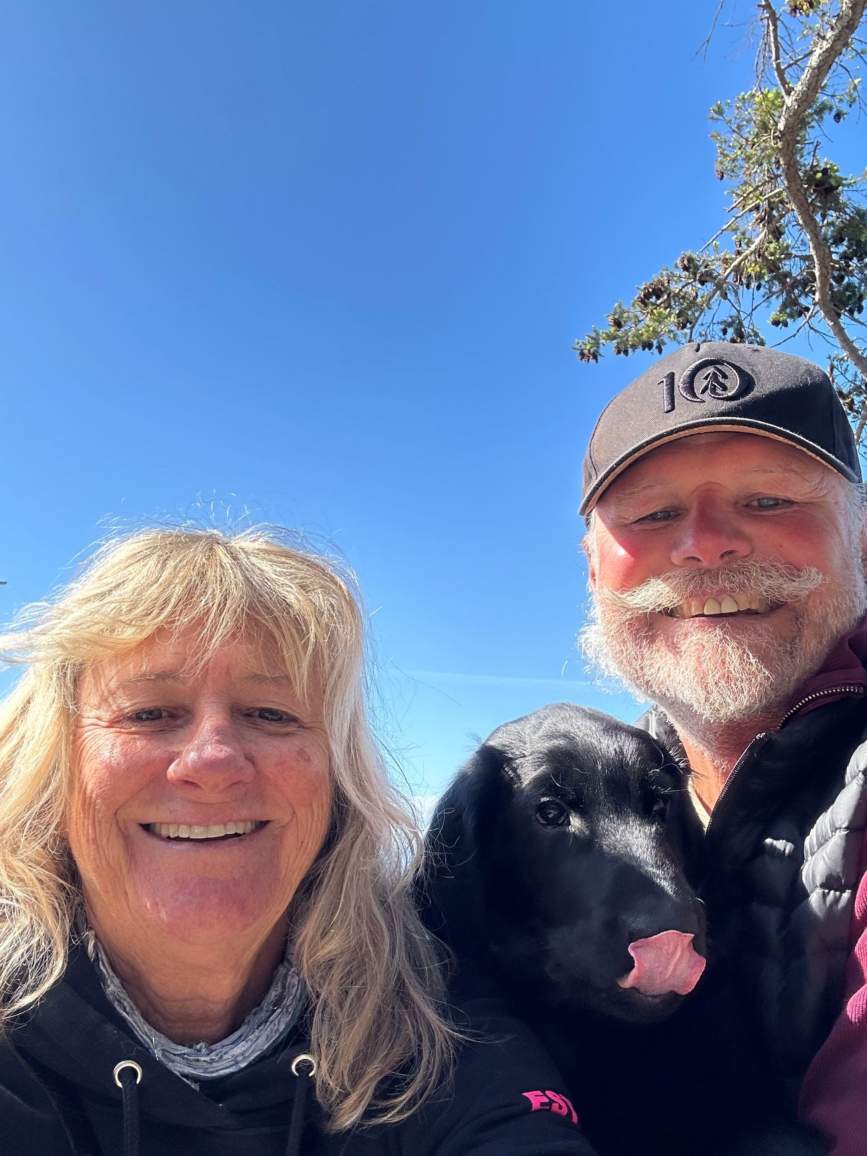A man and a woman are posing for a picture with their dog.